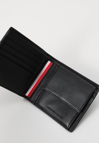 Zwarte leren portemonnee met meerdere kaartsleuven, een vak voor munten en een kleurrijke rood-wit-blauwe streepaccent aan de binnenkant.