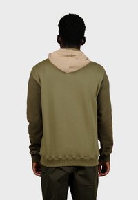 Sweat-shirt à capuche vert olive avec une capuche intérieure beige, des poignets et un ourlet côtelés, en tissu texturé, vu de dos.