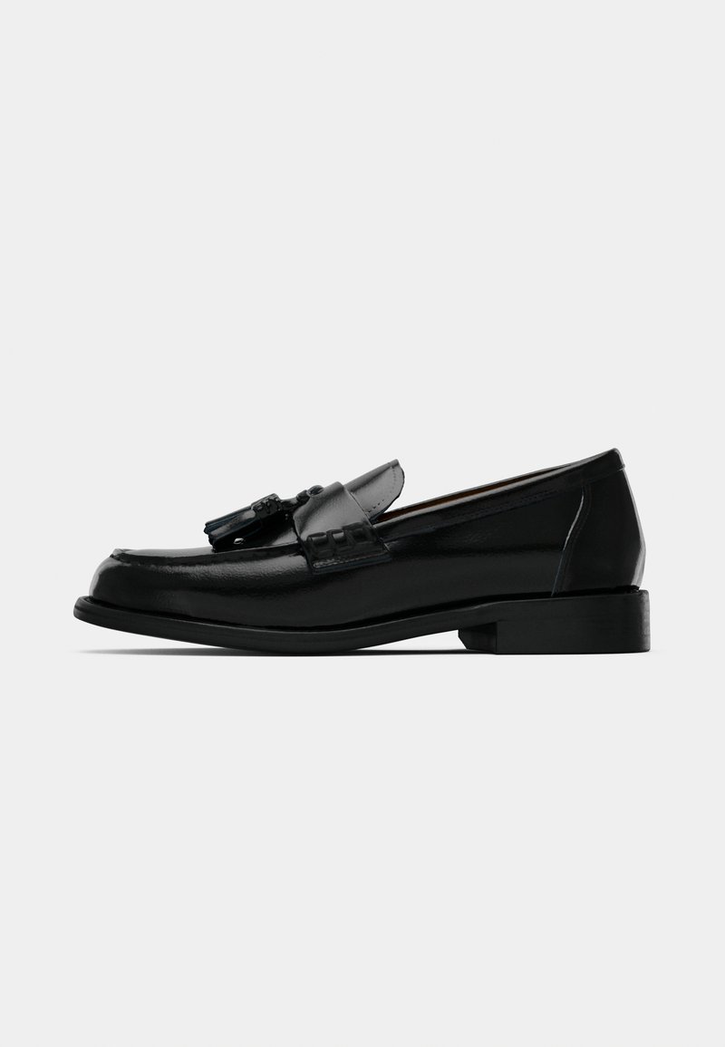 Black leather loafer with decorative tassels, low block heel, smooth texture, and rounded toe design, offering classic formal footwear style.