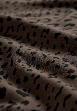 Hnědá tkanina s černým leopardím potiskem, ukazující měkkou texturu a jemné záhyby, zdůrazňující pružnost materiálu a jeho design.