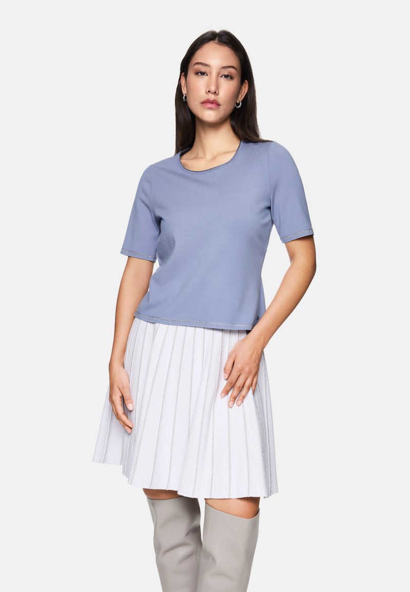 Helles blaues Kurzarmoberteil mit Rundhalsausschnitt; kombiniert mit einem weißen, gefalteten Rock mit silbernen Nadelstreifen; glatte Textur, lässige Passform.