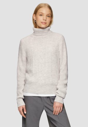 Pull en tricot gris clair avec un col roulé haut, présentant un motif en relief côtelé et des détails en tricot torsadé, associé à un pantalon gris.