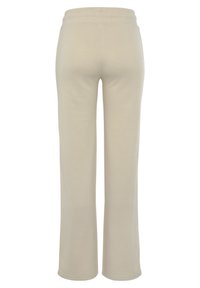 Lichtbeige wijde broek van zacht materiaal, met een elastische tailleband en een gladde textuur, zonder zichtbare zakken of logo's.
