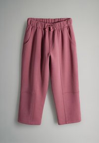 Rozā elastīgas jostasvietas bikses ar auklu, sānu kabatām un šūtiem ceļa detaļām, attēlotas pret neitrālu fona.