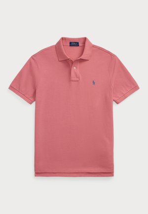 Rosa polo skjorta gjord av mjuk bomull med klassisk krage och en knappslå. Har en liten blå logotyp på vänster bröst.