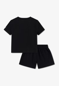 Σετ μαύρου αθλητικού ρουχισμού που περιλαμβάνει κοντομάνικη μπλούζα με λαιμόκοψη και ταιριαστό σορτς με ελαστική μέση. Ομαλή υφή.