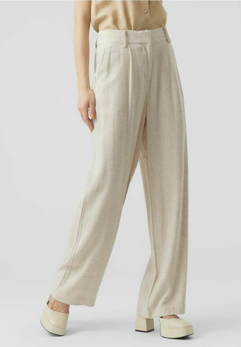 Beżowe, wysokie spodnie wykonane z lekkiej mieszanki lnu, z zakładkami i luźnym krojem. Posiadają boczne kieszenie oraz przeszywane detale szwów.