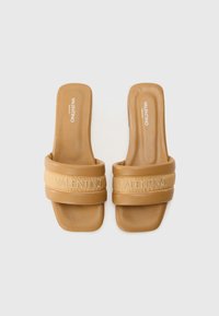 Sandales à glissière en cuir tan avec de larges brides arborant le logo "Valentino" en relief. Texture lisse avec une semelle intérieure rembourrée.