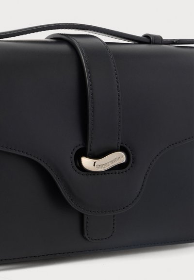 Μαύρη δερμάτινη γυναικεία τσάντα με επάνω χερούλι και καμπυλωτό καπάκι, ασφαλισμένο με χρυσό κούμπωμα χαραγμένο με την επιγραφή «Emporio Armani».