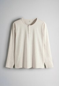Beige long-sleeve henley shirt with three buttons on a round neckline, hanging against a plain light gray background.