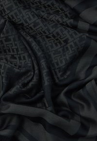 Sort tørklæde med et diskret geometrisk mønster og en glat tekstur, i varierende nuancer af mørkegrå og med frynser.