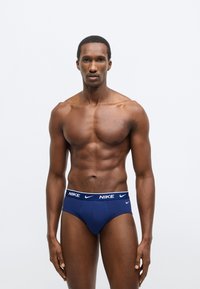 Ανδρικά εσώρουχα Nike σε ναυτικό μπλε, με λευκή ζώνη μέσης με λογότυπο. Κατασκευασμένα από απαλό ύφασμα με λεία υφή, σχεδιασμένα για εφαρμοστή γραμμή.