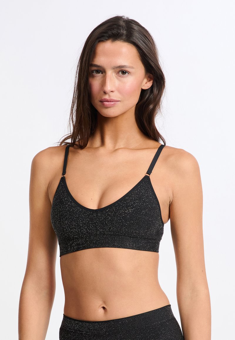 Czarny biustonosz typu bralette z dekoltem w kształcie litery V, wykonany z miękkiego materiału i posiadający cienkie ramiączka z metalowymi akcentami. Tkanka ma delikatny połysk.