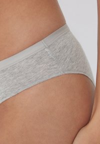 Šedé spodní prádlo s jemnou, hladkou texturou; má jednoduchý design a tenký pas. Podrobnosti švů jsou viditelné podél okrajů.