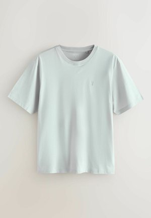 T-shirt à manches courtes gris clair en coton doux. Design classique à col rond avec un logo subtil sur la poitrine gauche. Texture lisse.