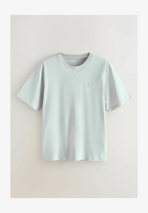 T-shirt à manches courtes gris clair en coton doux. Design classique à col rond avec un logo subtil sur la poitrine gauche. Texture lisse.