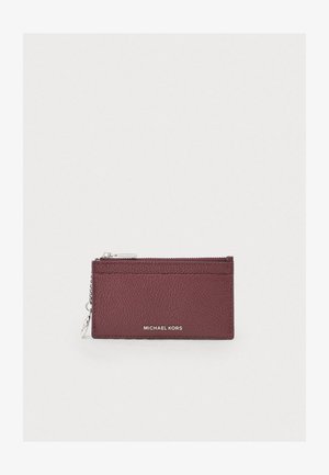 Burgundijas teksturētas ādas kartes turētājs ar ciklu nodalījumu, sudraba detaļu akcentiem un "MICHAEL KORS" logotipu priekšā.