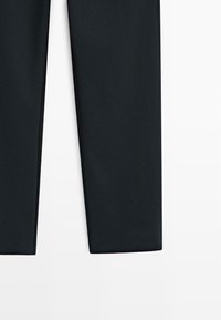 Pantaloni neri aderenti realizzati in tessuto liscio ed elastico. Presentano una vita piatta e gambe sagomate con dettagli di design minimali.