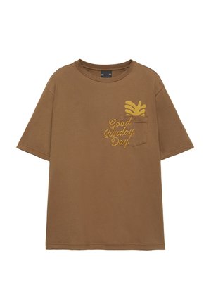 T-shirt marron à manches courtes avec une poche poitrine, un dessin de feuille jaune et les mots "Good Sunday Day" imprimés à côté de la poche.