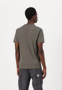 Tricou din bumbac gri cu gât rotund și mâneci scurte, prezentat din spate. Are o croială dreaptă și cusături curate.