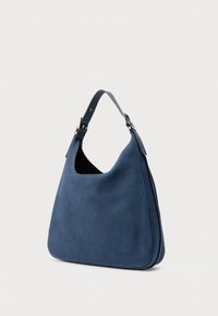 Mala hobo azul em camurça com uma única alça de ombro ajustável e fivelas de metal prateado, exibida contra um fundo branco simples.