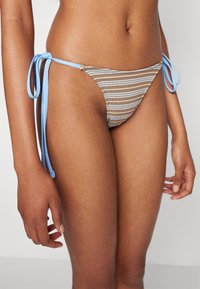 Brun og beige stripete bikini-bunn med lyseblå snøring på sidene. Den har en teksturert overflate og lav midje for minimal dekning.