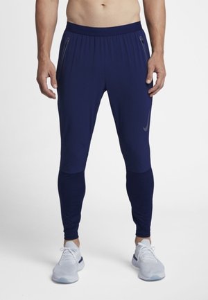 Marineblaue Sporthosen mit schmalem Schnitt, ausgestattet mit Reißverschlusstaschen und kontrastierendem Stoff am unteren Bein. Weiches, dehnbares Material.