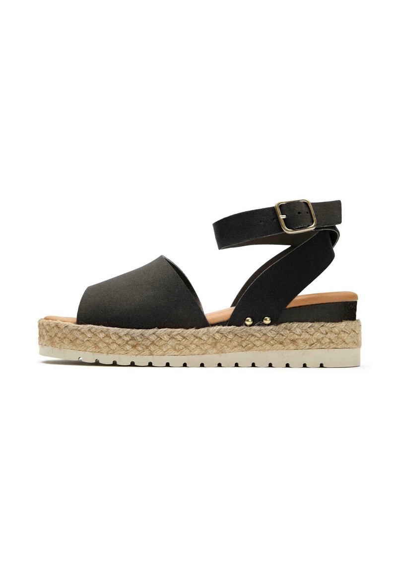 Black sandal with wide fabric strap, ankle buckle, and woven jute platform. Features a cushioned insole and textured rubber outsole.