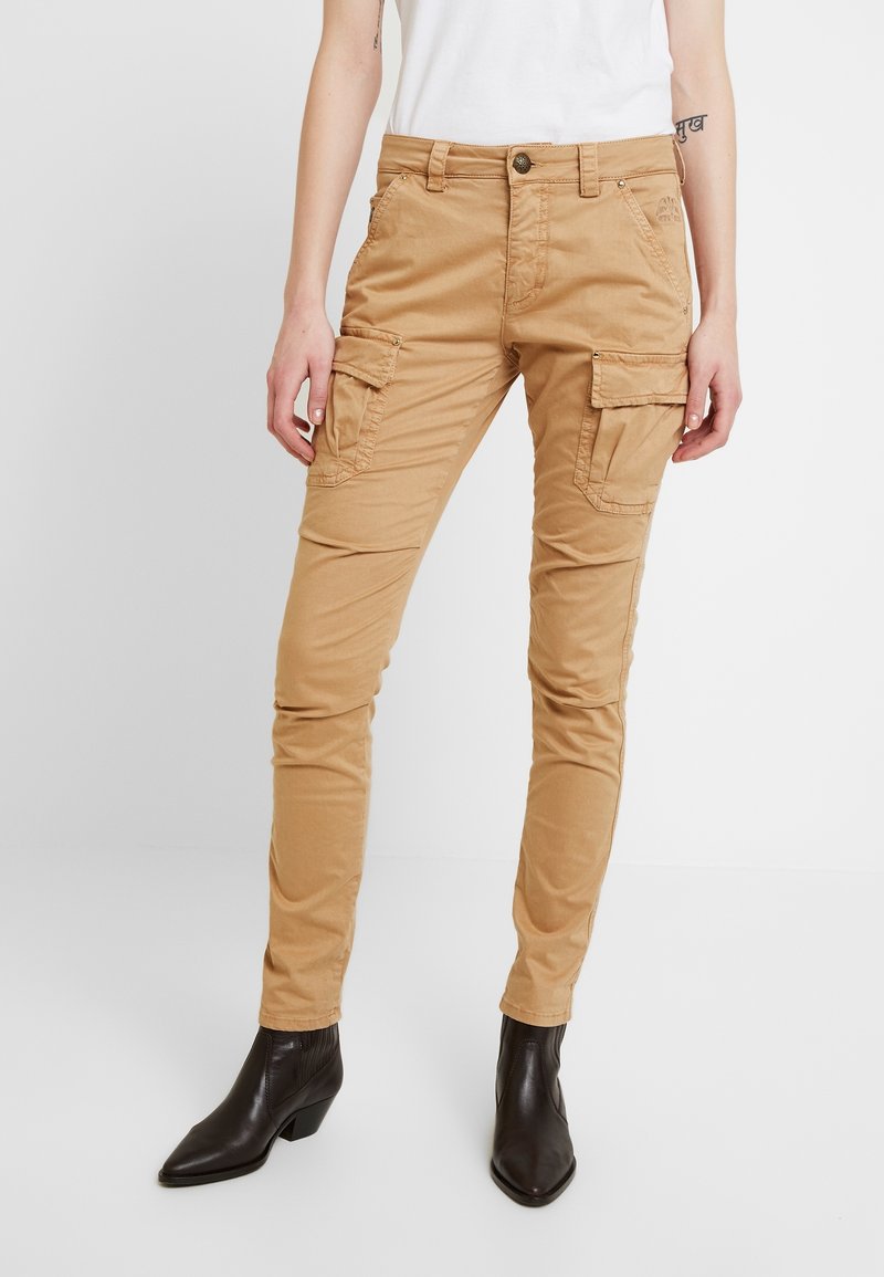 Khaki cargo-housut slim fit -mallilla, joissa on sivutaskut, sileä pinta ja kestävä napitus. Yhdistetty tummiin nilkkabootseihin.