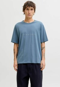 Sinine puuvillane T-särk lühikeste varrukatega, keskel valge "JACK & JONES" logoga. Riie on siledapinnaline.