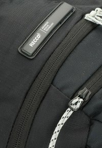Zwarte rugzak met een textuurstof, contrasterende ritslus met touwwerkdetail en een label met de tekst "RECCO® ADVANCED RESCUE TECHNOLOGY."