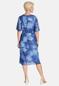 Blaues Blumenkleid mit kurzen Ärmeln, leichtem Stoff, elastischem Bund, knielangem Saum und weichem Aquarellmuster in verschiedenen Blautönen.