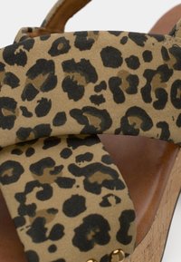 Σανδάλια με πλατφόρμα σε καμηλό λεοπάρ σχέδιο και διασταυρούμενες λωρίδες. Φτιαγμένα από συνθετική σουέτ, με μπεζ φόντο και μαύρο λεκέδες. Σόλα από φελλό.