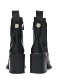 Par de botas de tobillo de cuero negro con tacones de bloque, cremallera trasera y logotipo plateado de BOSS en las pestañas para tirar.