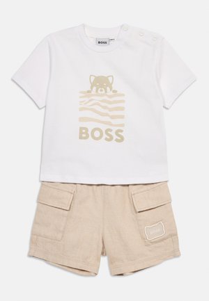 Weißes Kurzarmhemd mit beiger Katze und dem Schriftzug "BOSS", kombiniert mit beigen Cargoshorts mit Seitentaschen und Katzen-Patch.
