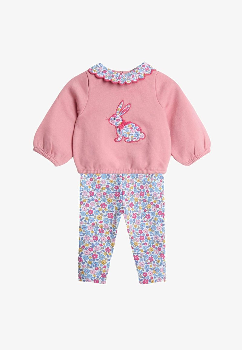 Sweat-shirt rose avec un col en dentelle florale et une appliqué de lapin ; associé avec des leggings blancs présentant un motif de fleurs colorées.