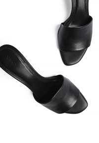 Črne usnjene natikače z širokim trakom, odprtim prstom in kvadratnim peto. Gladka tekstura s subtilnimi šivi.