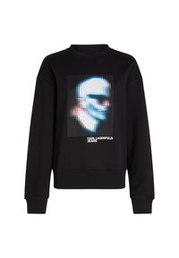 Melna džemperis ar ribotu apkakli, kurā ir centrālā grafika ar izkropļotu seju un teksts "KARL LAGERFELD JEANS" zem tās.