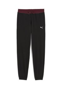 Sorte joggingbukser med en burgunder farvet elastisk talje, snøre, to sidelommer og hvid Puma-logo på venstre ben.