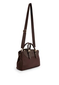 Hnědá syntetická kabelka s dvojitými uchy a nastavitelným popruhem. Má zlaté kovové doplňky a texturovaný panel na přední straně.