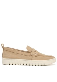 Beige suede instappers met een flexibele witte rubberen zool, voorzien van een gestikt ontwerp en een decoratieve band over de bovenkant.