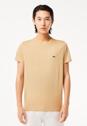 T-shirt beige in cotone con maniche corte e scollatura rotonda, caratterizzata da un piccolo logo verde sulla parte sinistra del petto.