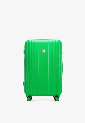 Zielona walizka twarda z pionowymi żłobieniami, teksturowaną powierzchnią i metalowym logo. Wyposażona w cztery koła umożliwiające łatwe przemieszczanie się.