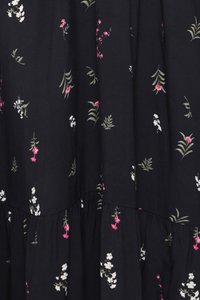 Sort stof med spredte små hvide og pink blomstermønstre og grønne blade, med rynkede lagdelte sømme.