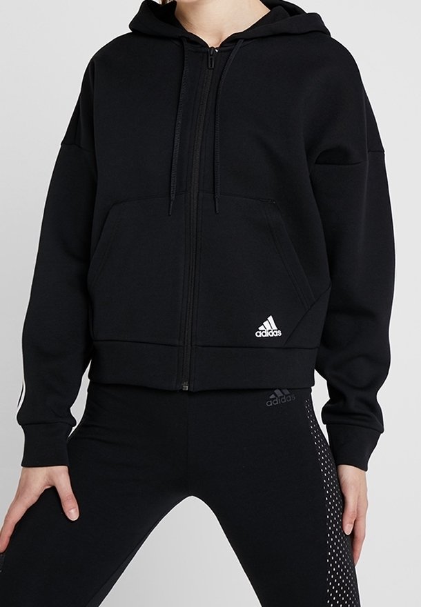 Felpa nera con zip realizzata in materiale morbido, con tasca a marsupio, cappuccio e logo Adidas bianco sul davanti. Design aderente.
