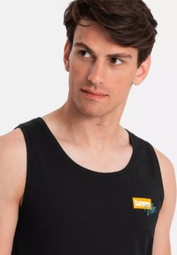 Svart ärmlös linne med en färgglad "Summer Vibe" logotyp. Tillverkad av mjuk bomull, har den en klassisk passform och en rund halsringning.