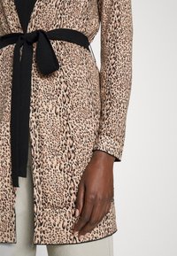 Beżowo-czarny płaszcz w panterkę z długimi rękawami, wiązanym paskiem oraz miękką fakturą o gładkim wykończeniu.