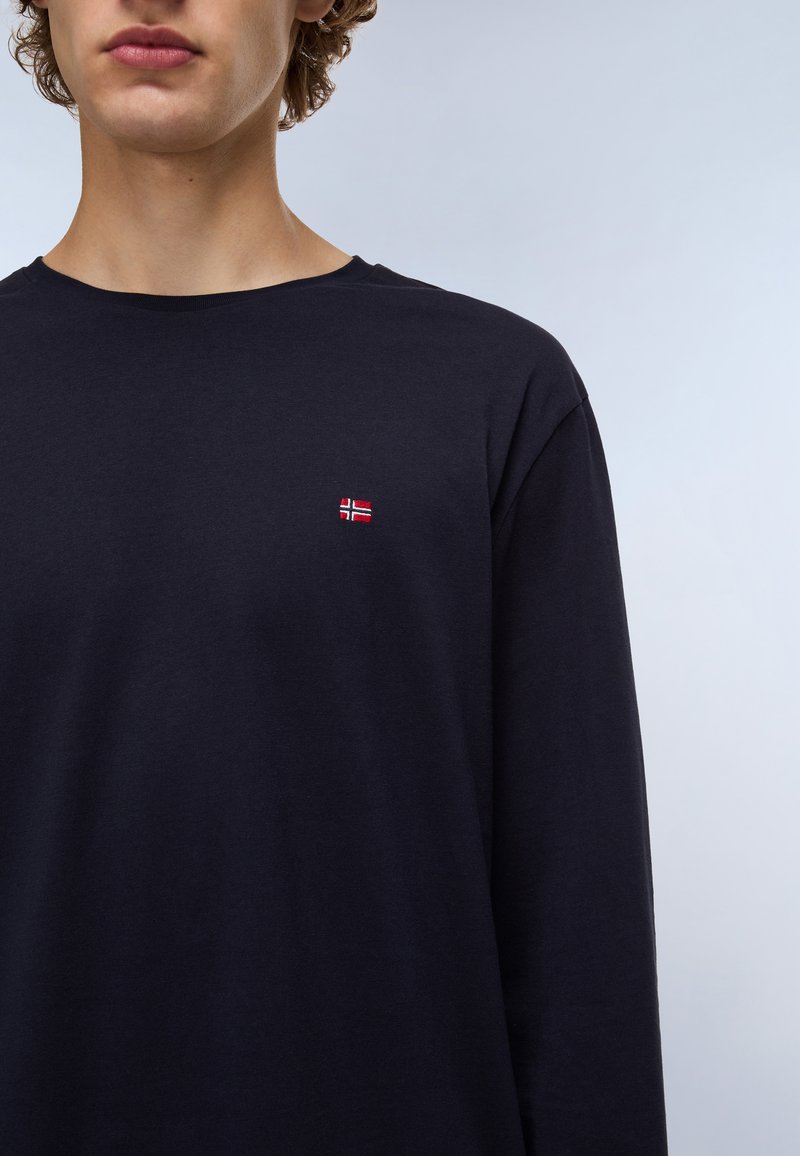 Camisa de manga larga en color marino con una pequeña bandera noruega bordada en el pecho. Confeccionada en suave algodón y con un cuello redondo.