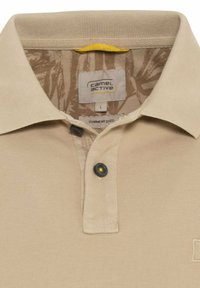 Beżowa koszulka polo farbowana w masie, z kołnierzykiem, z zapięciem na guziki w ciemnym kolorze oraz teksturowanym wzorem wewnętrznym. Metka: Camel Active, rozmiar L.