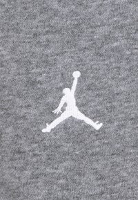 Szürke anyag, amelyen egy fehér hímezett Jumpman logó látható, ami egy ugrás közben lévő figurát ábrázol, aki kosárlabdát tart a kezében. Puha tapintás, sportos dizájn.